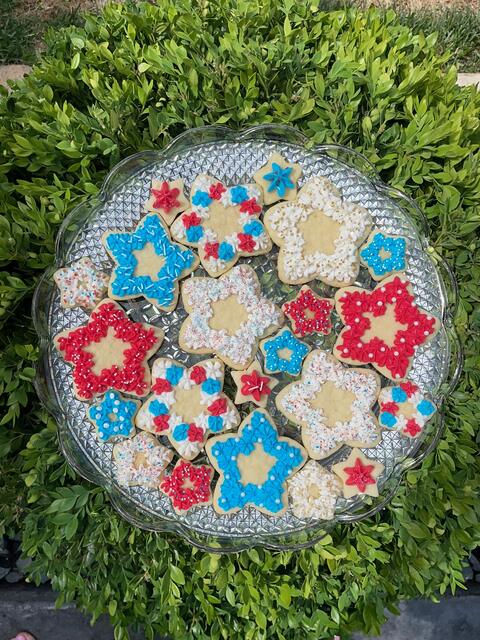 Red, white and blue star-shaped decorated sugar cookies on a cut-glass plate outdoors