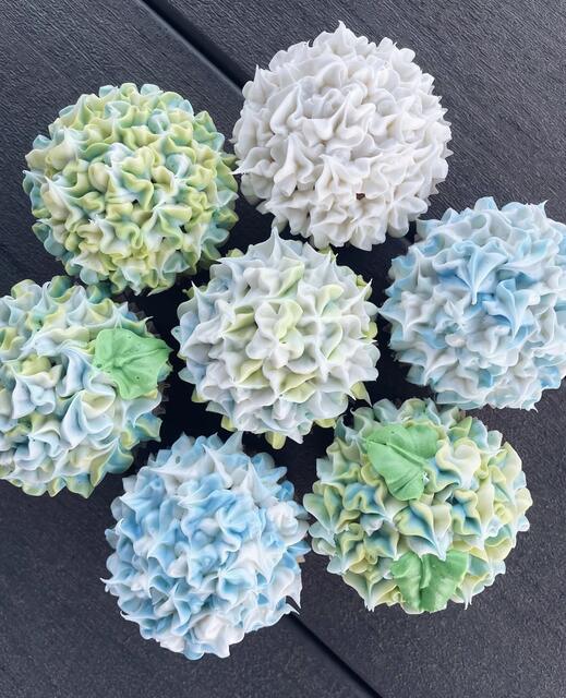 Cupcakes piped with ruffled buttercream to resemble blue, green and white hydrangea blooms